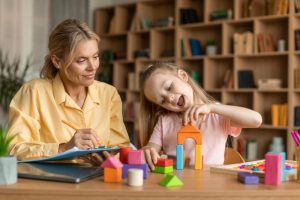 child psychology exam little girl playing with colorful wooden blocks professional kids psychologist writing notes - Oyun Terapisi Nedir ?